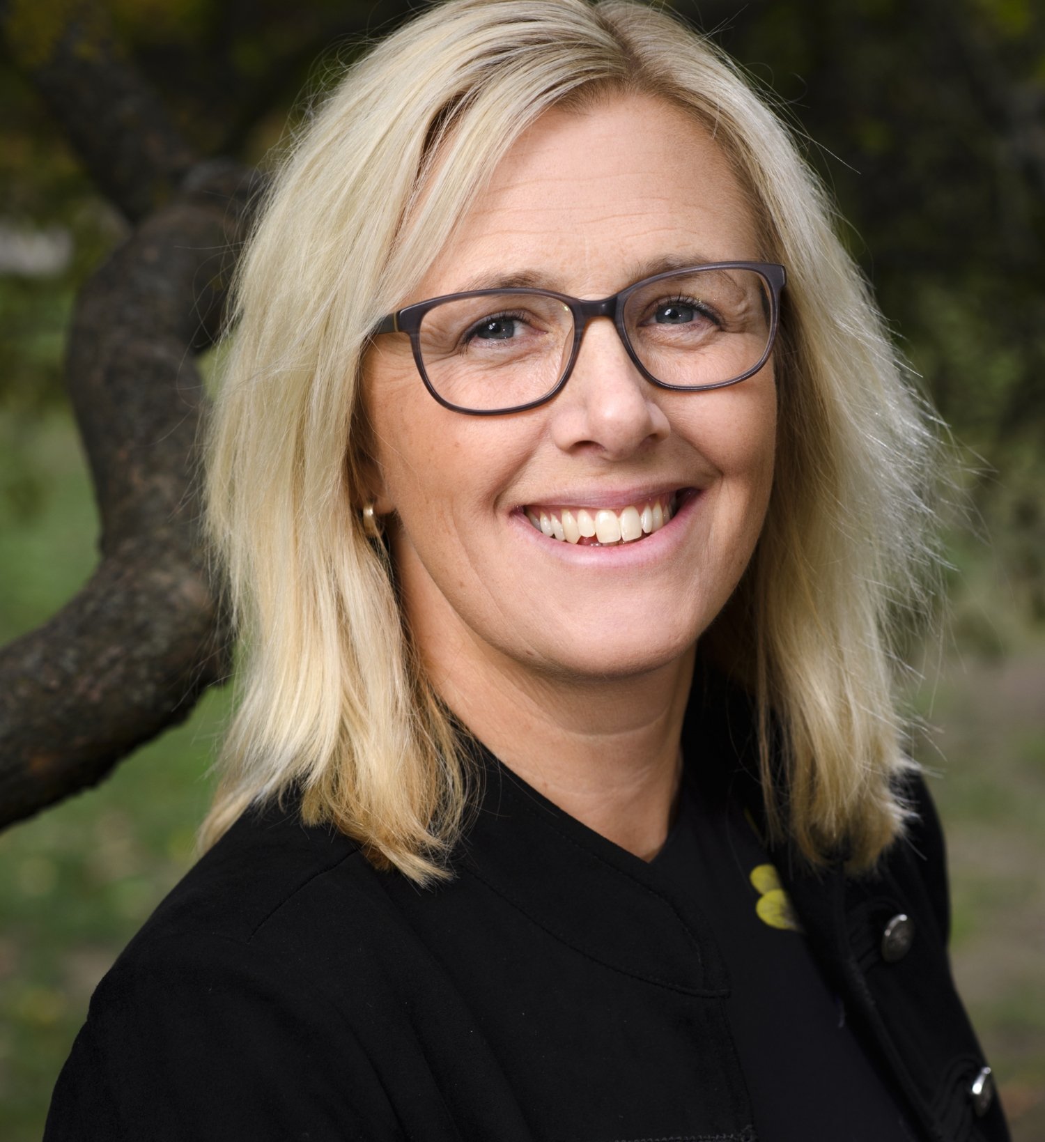 a smiling woman with middle length hair, glasses and a fineknitted sweater