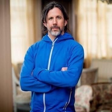 Photo of Jason Murphy. A man in a blue jumper with arms crossed over his chest