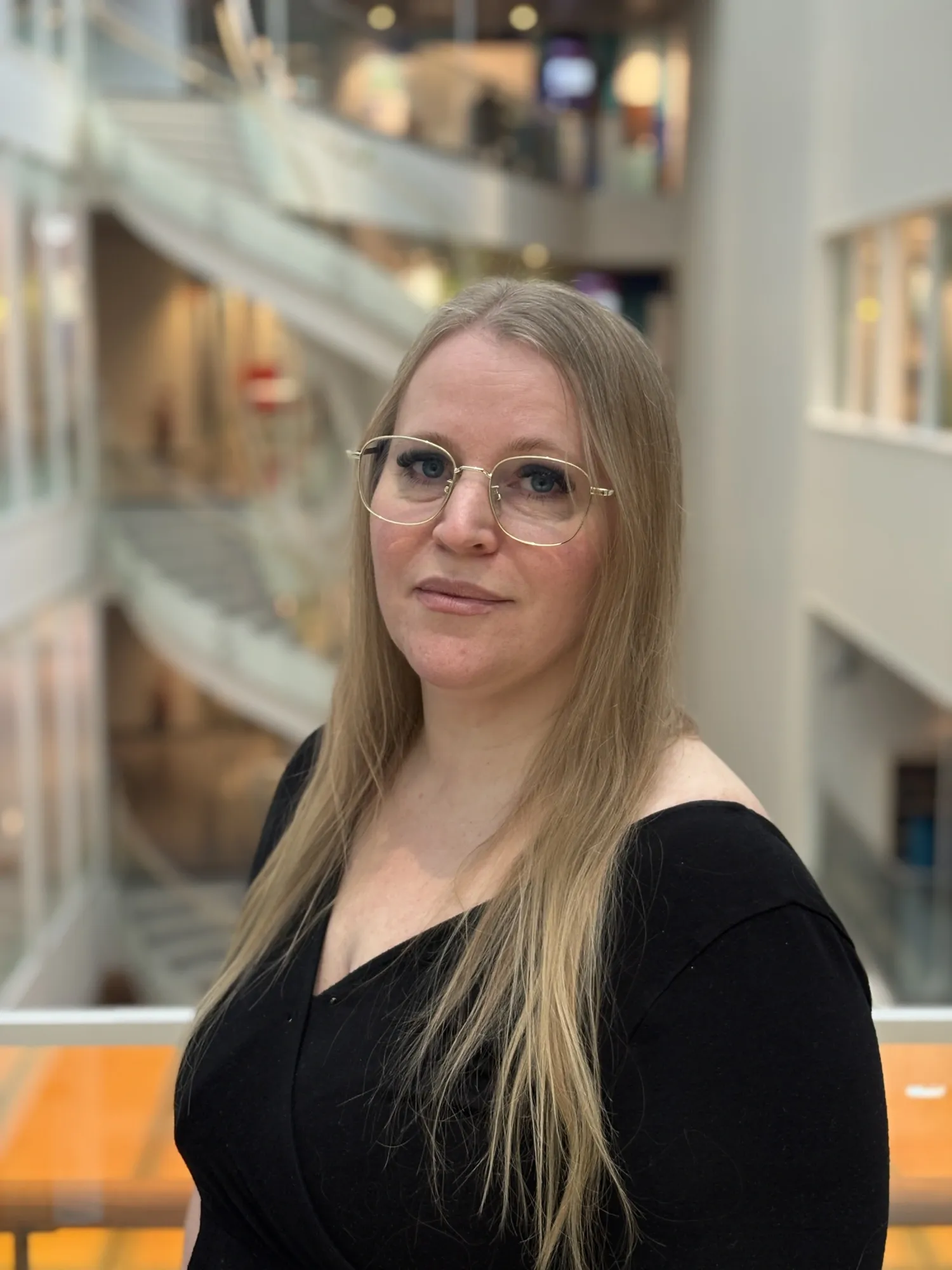 Portrait of a blonde woman wearing glasses and a black shirt.