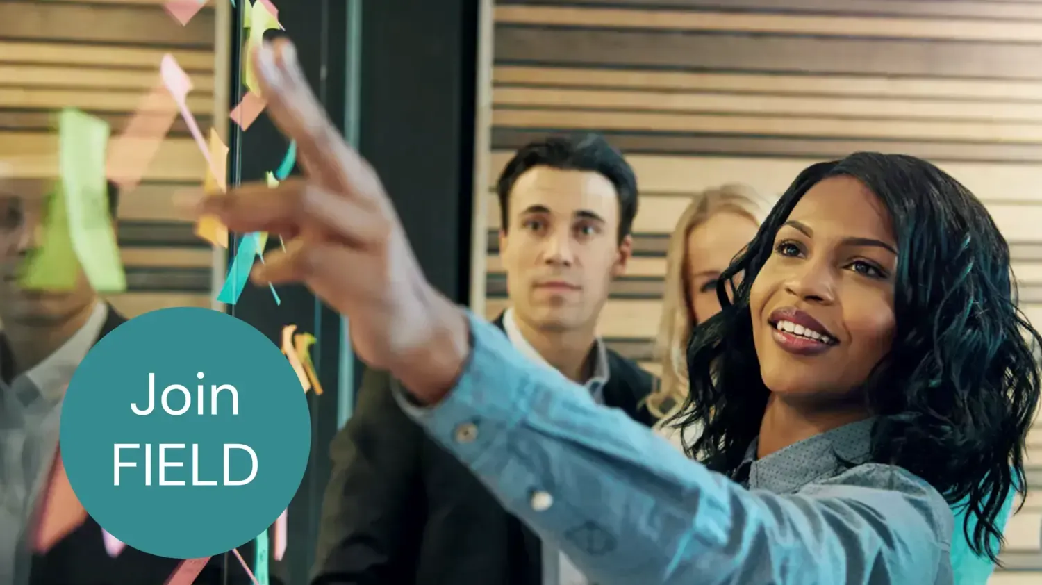 Black woman putting post it-notes on glass board.