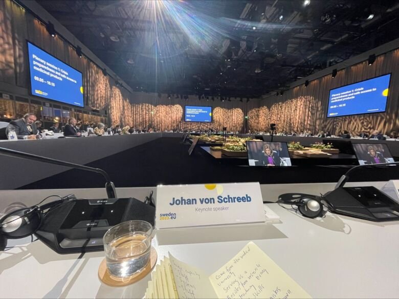 Photo of a desk with a name tag and people standing in the background