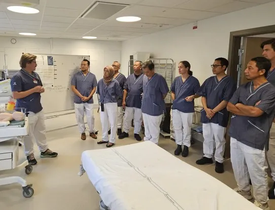 Group of people listening to a man in a hospital environment.