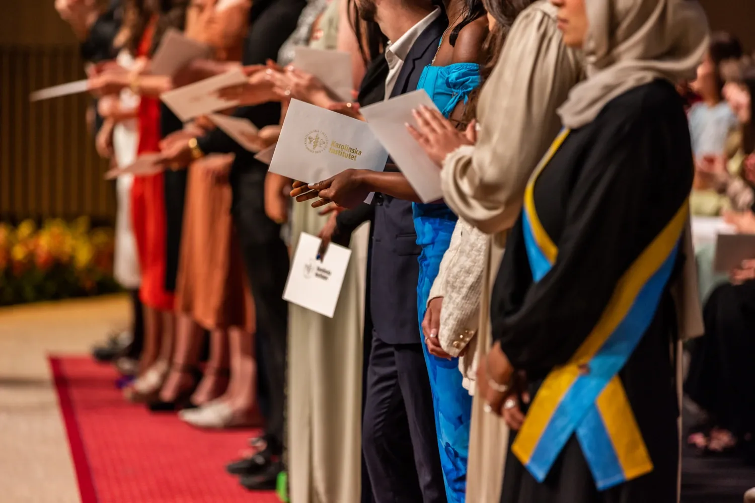 Hands of graduating students holding their diplomas in Aula Medica.