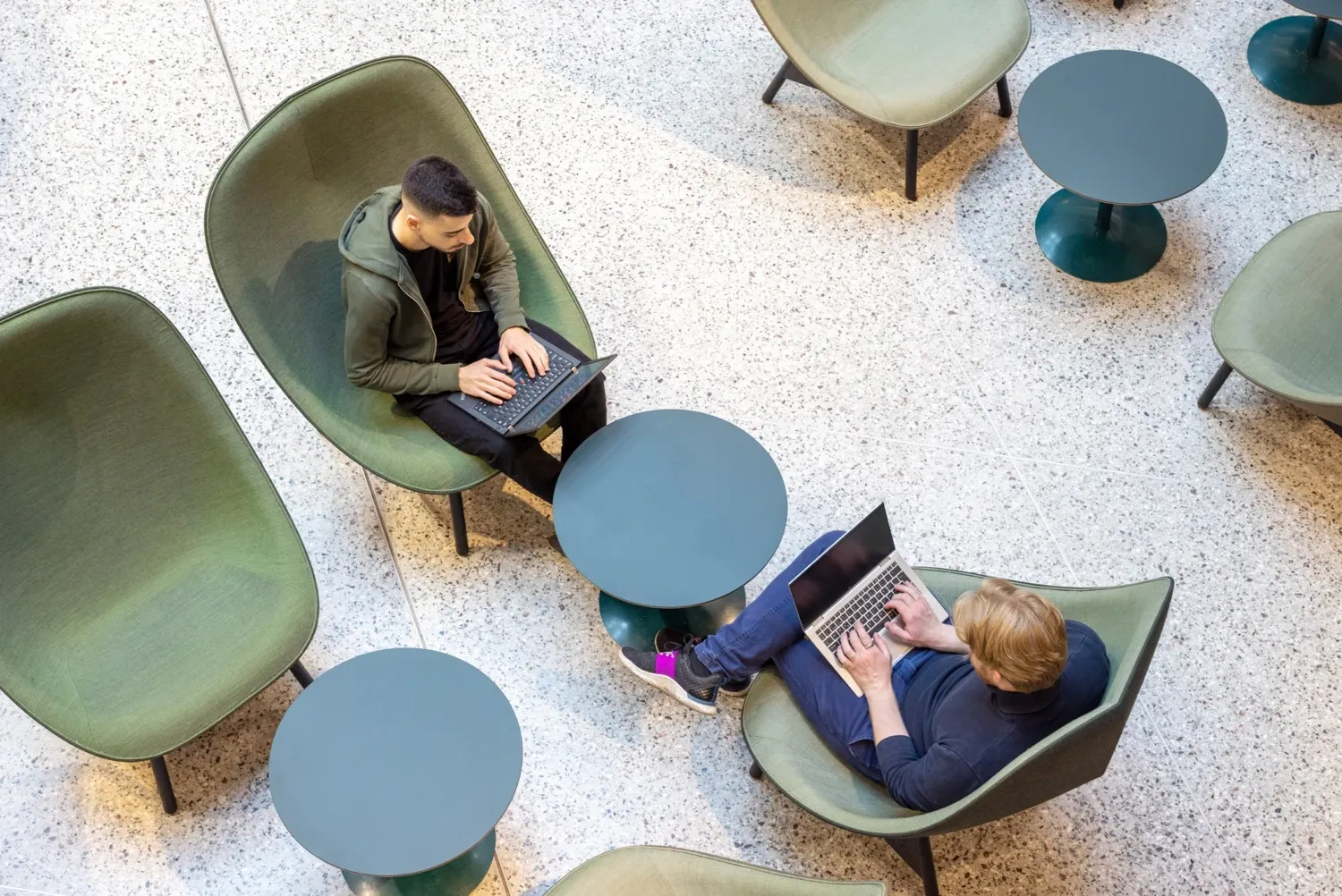 Two students sitting with their laptops studying at campus Solna.
