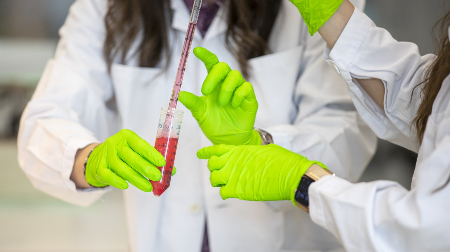 Hands working with pipette and test tubes.