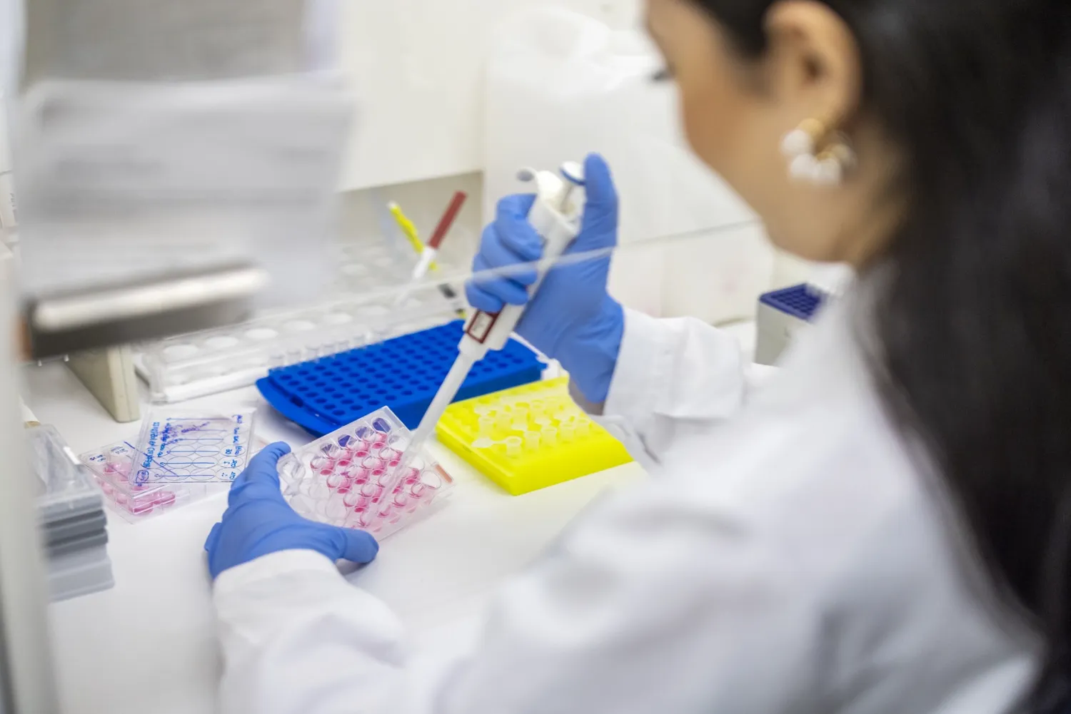 Hands working with pipette and test tubes.