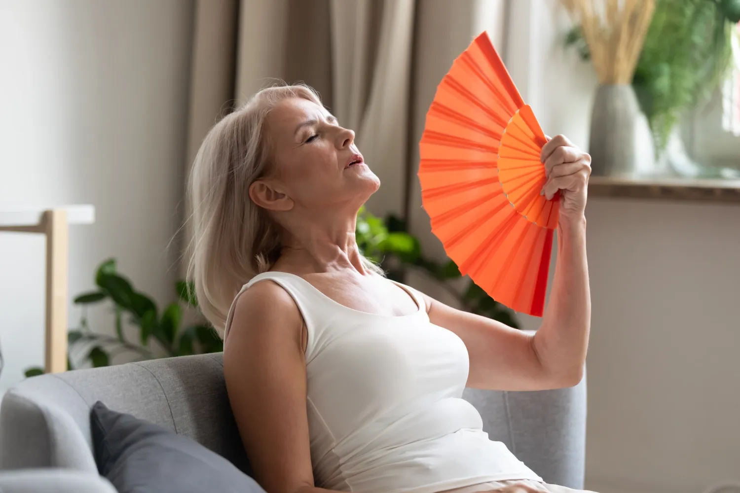 Image of a woman in menopause with a hand fan