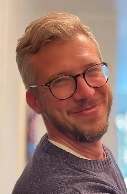 Portrait photo of a smiling man with glasses.
