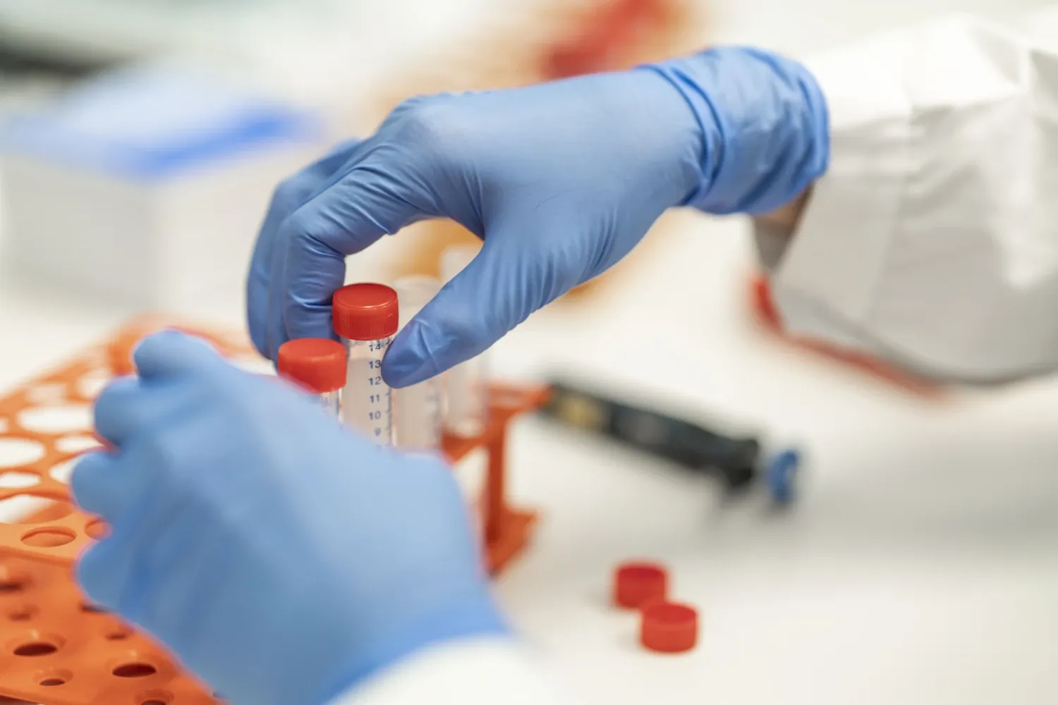 Hands in gloves, sorting small bottles in the lab.