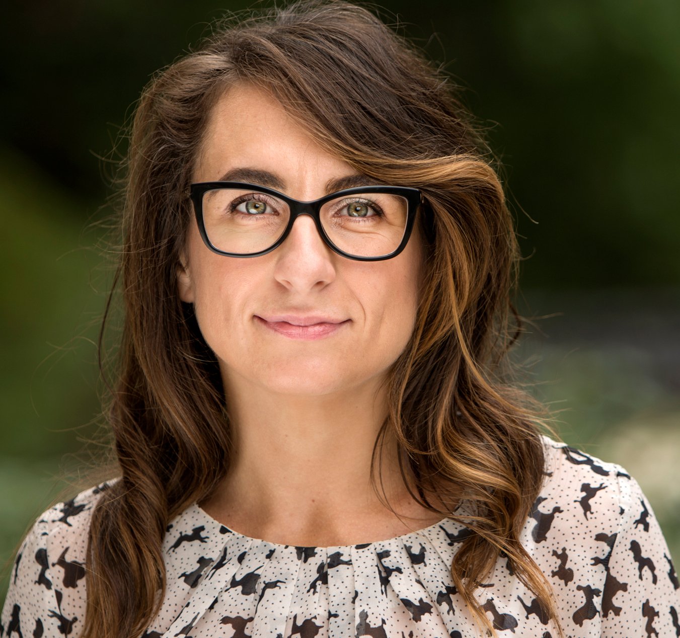 Portrait of a women with dark hair and glasses.