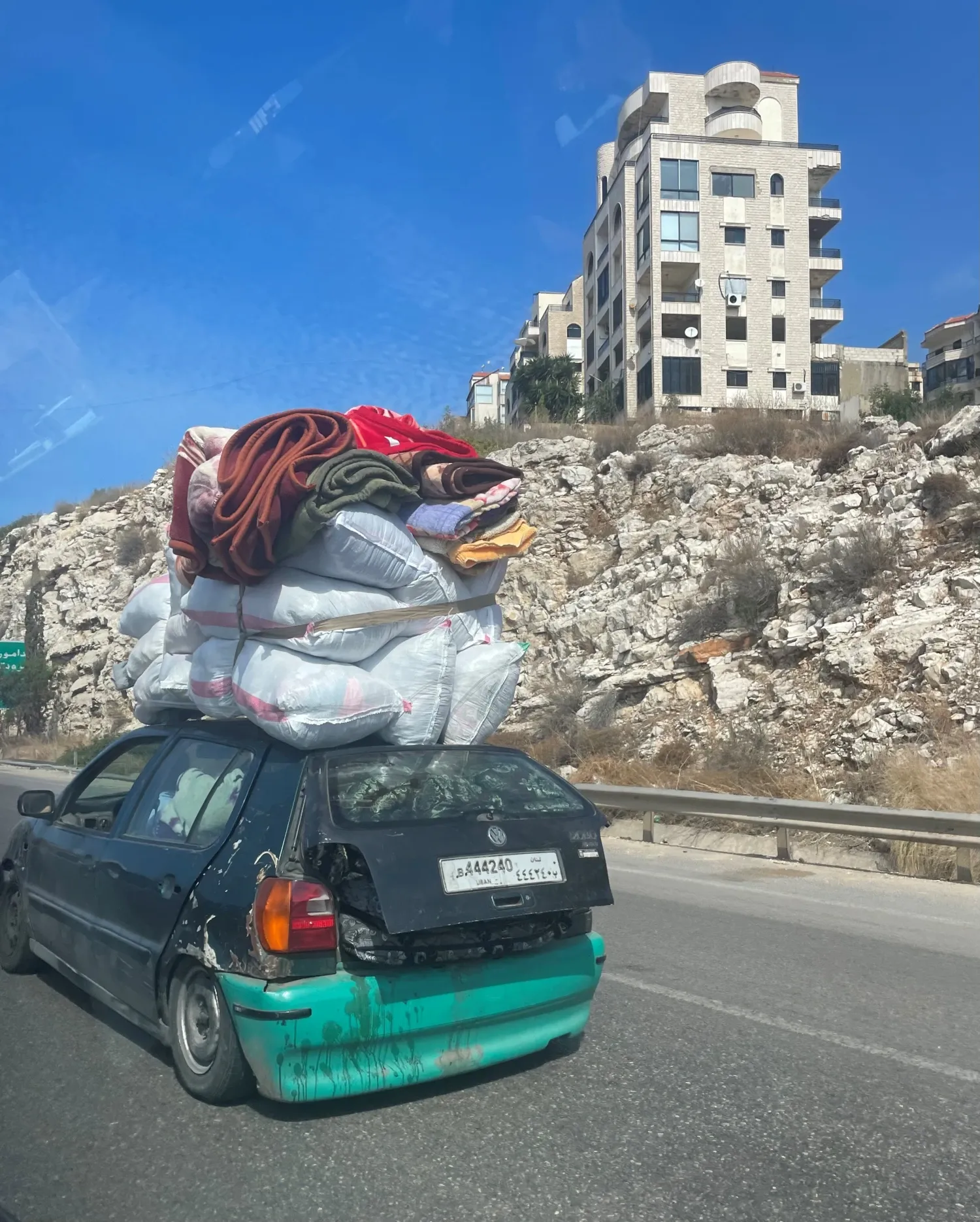 A heavily packed old car on a road