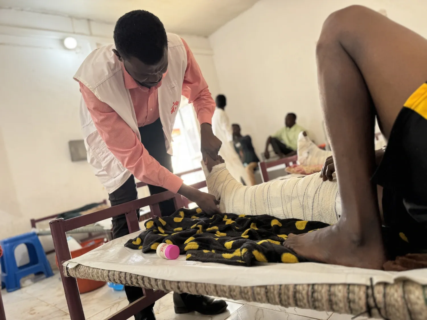 Johan von Schreeb in front of rows of green tents set up on dry ground with snow-capped mountains in the background under a clear blue sky.