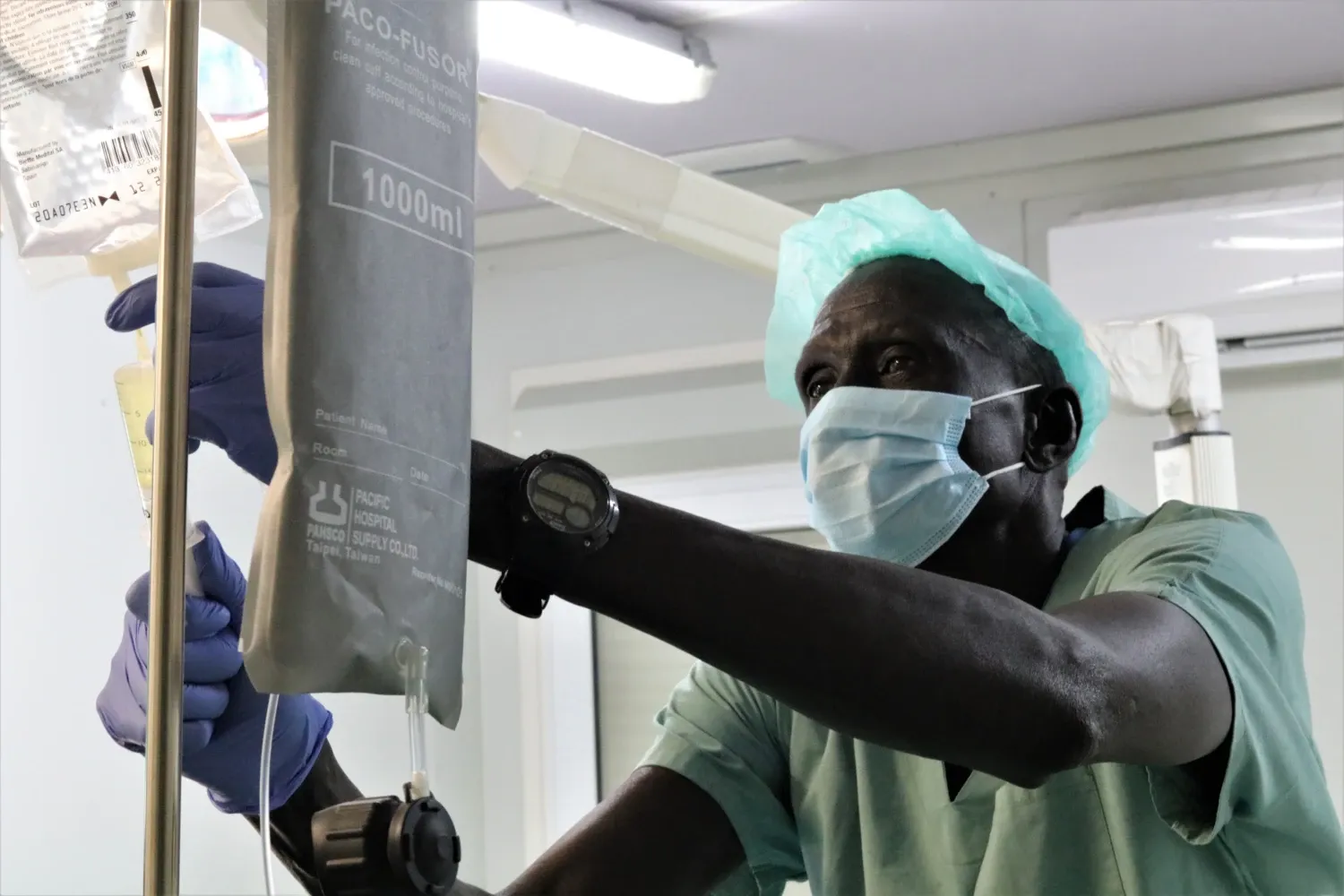 A doctor places a drip bag on a stand