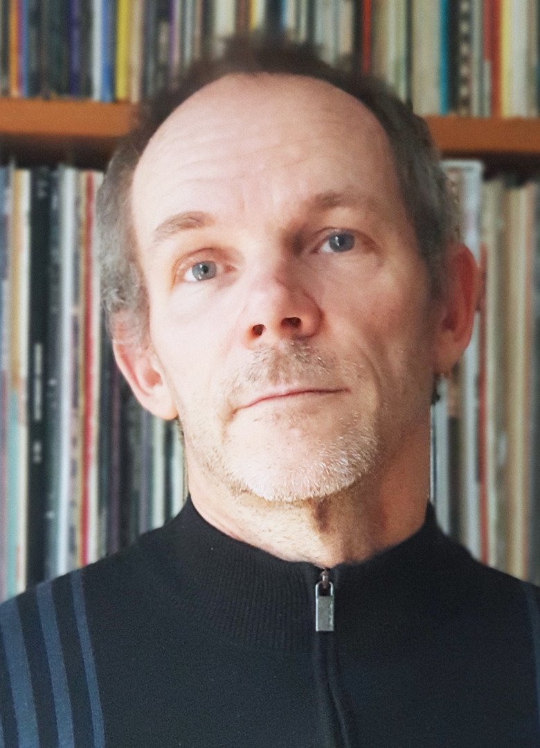 Portrait of Magnus in front of a book shelf.