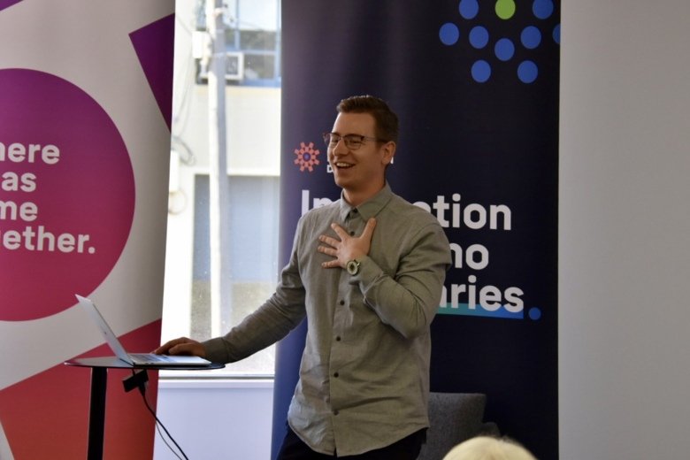 Max Kleijberg presenting his research at the RMIT Health Transformation Lab, Melbourne, Australia. Standing with his computer, smiling, putting his left hand over his heart.