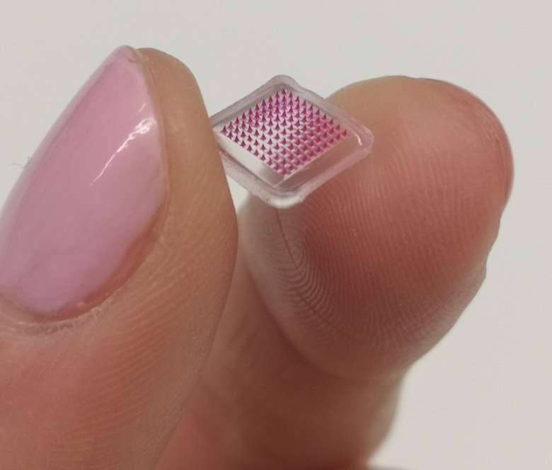 Fingers holding the microneedle patch