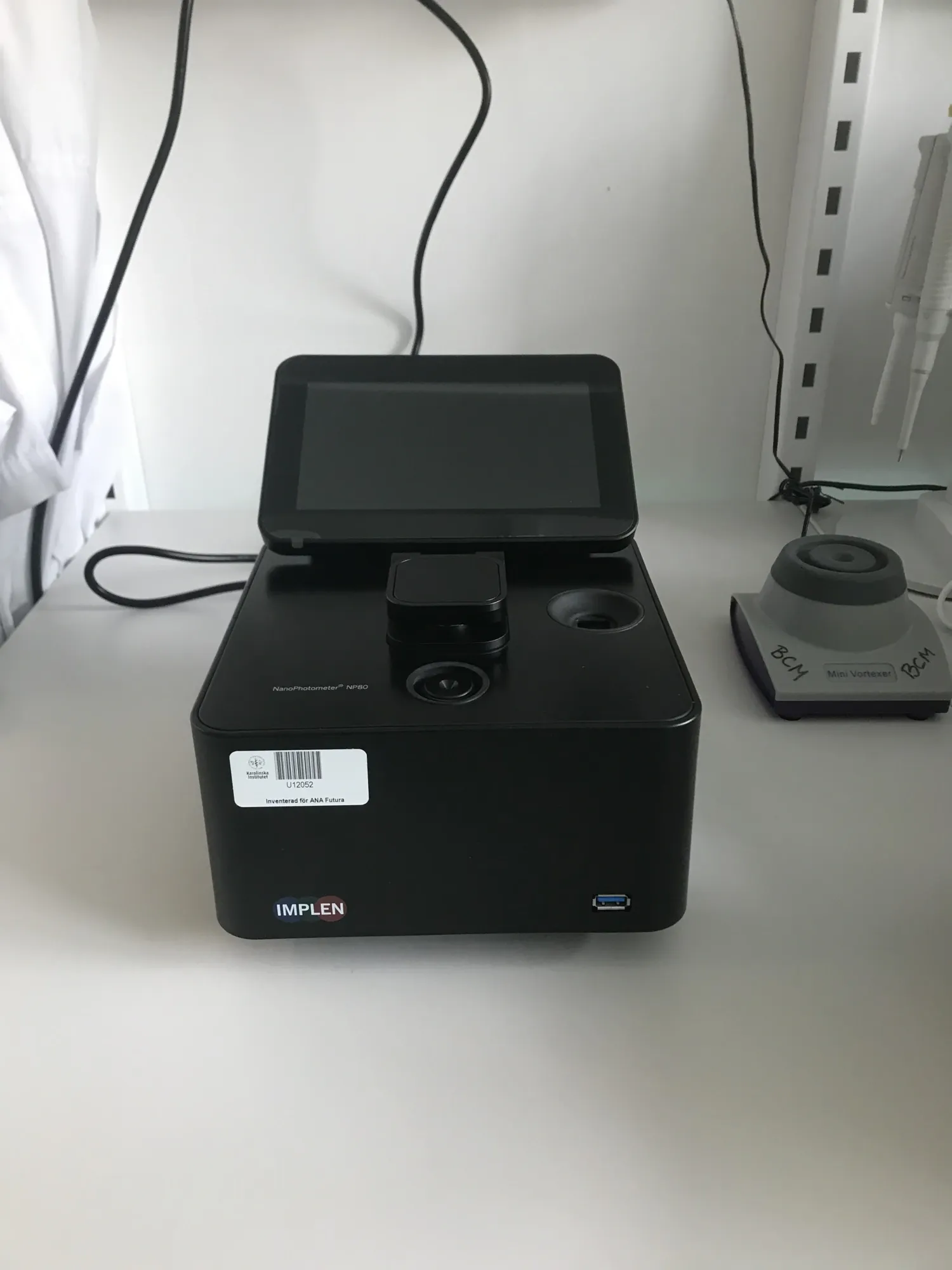 Photo of a black NanoPhotometer™ NP80 instrument standing on a table.