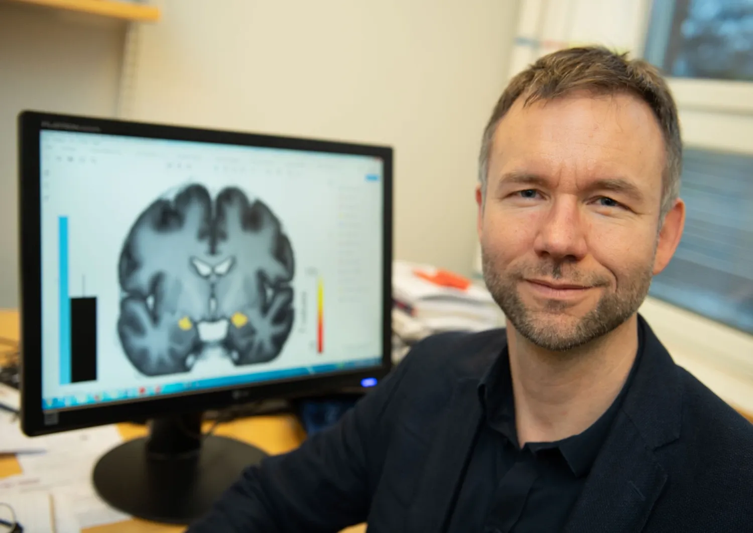 Andreas Olsson in front of a screen that shows a brain
