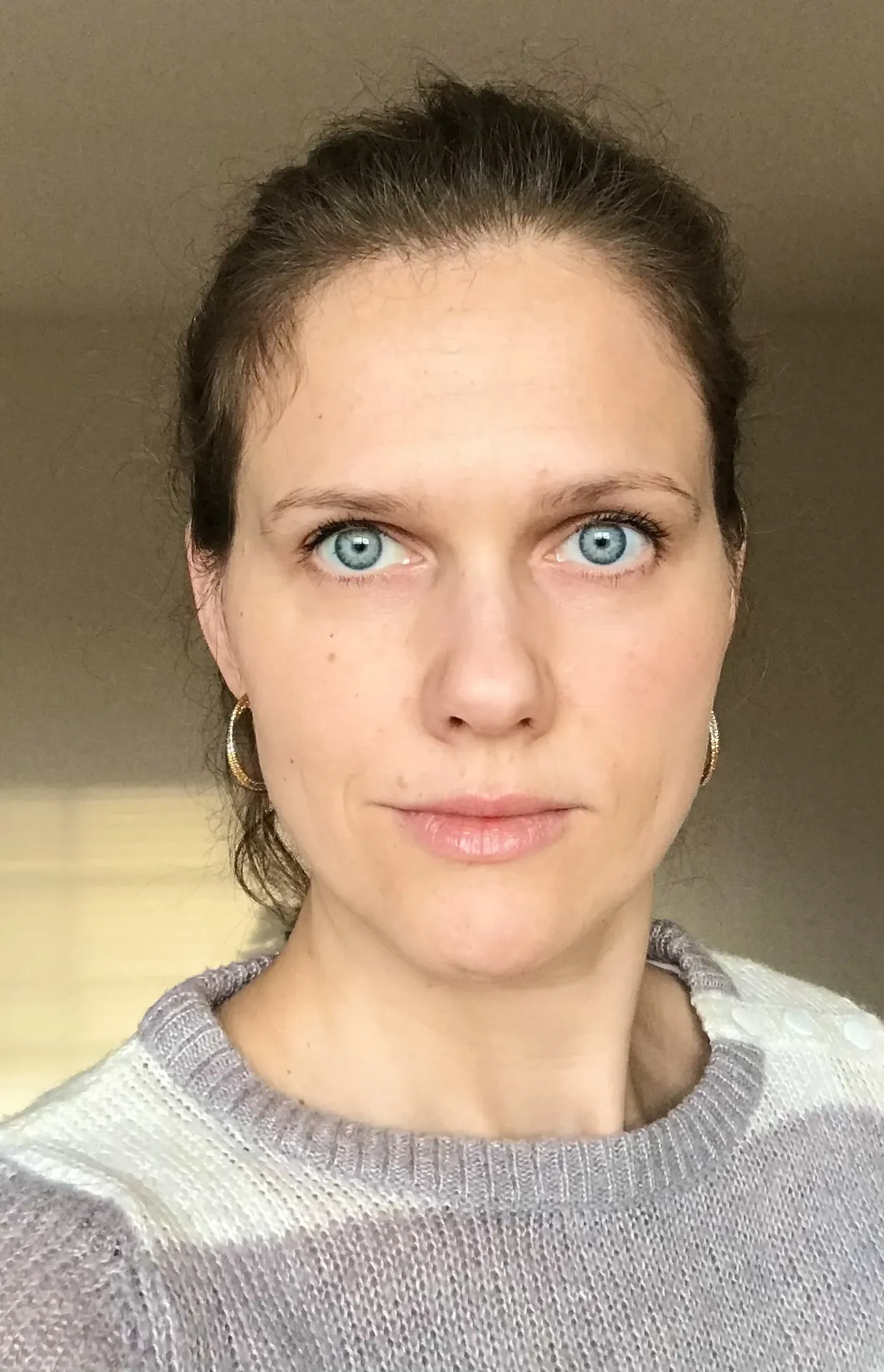 Portrait photo of a woman with blue eyes and her hair up.