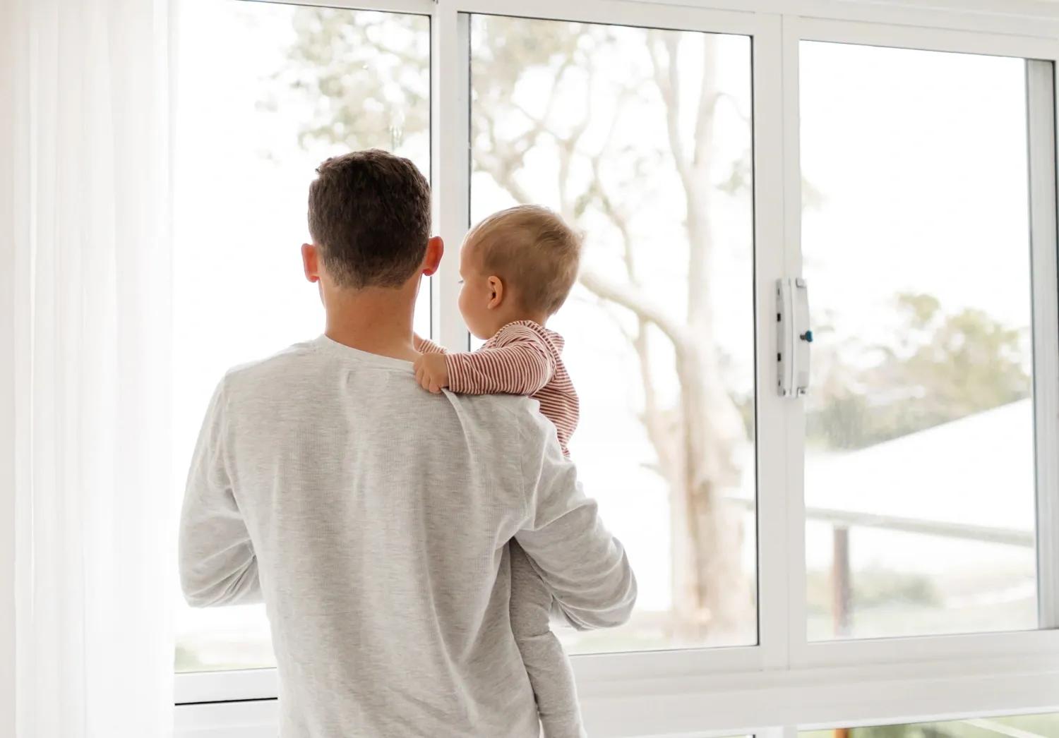 Father holding child looking out a window