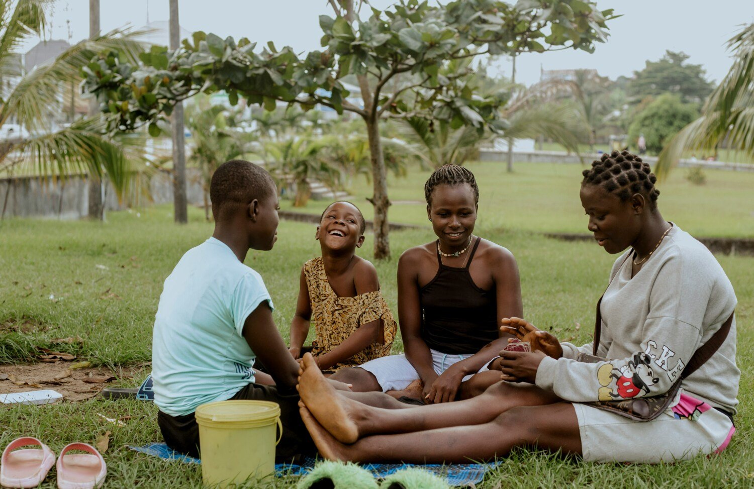 Group of people sitting in the grass and playing card