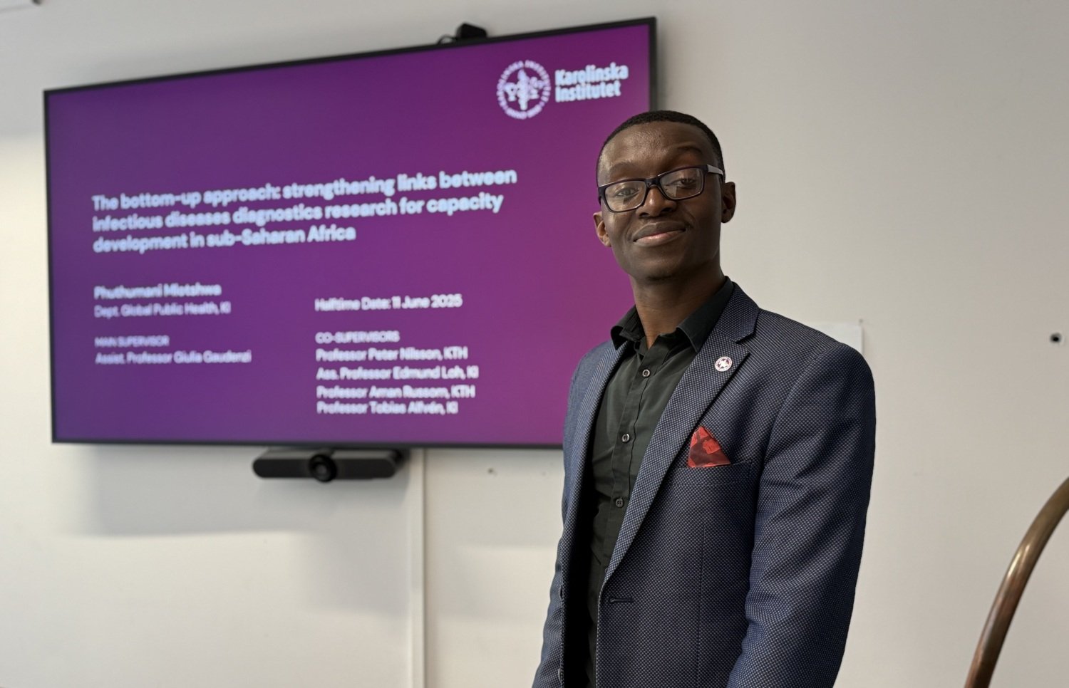 PhD student Phuthumani standing in front of a screen presenting his project.
