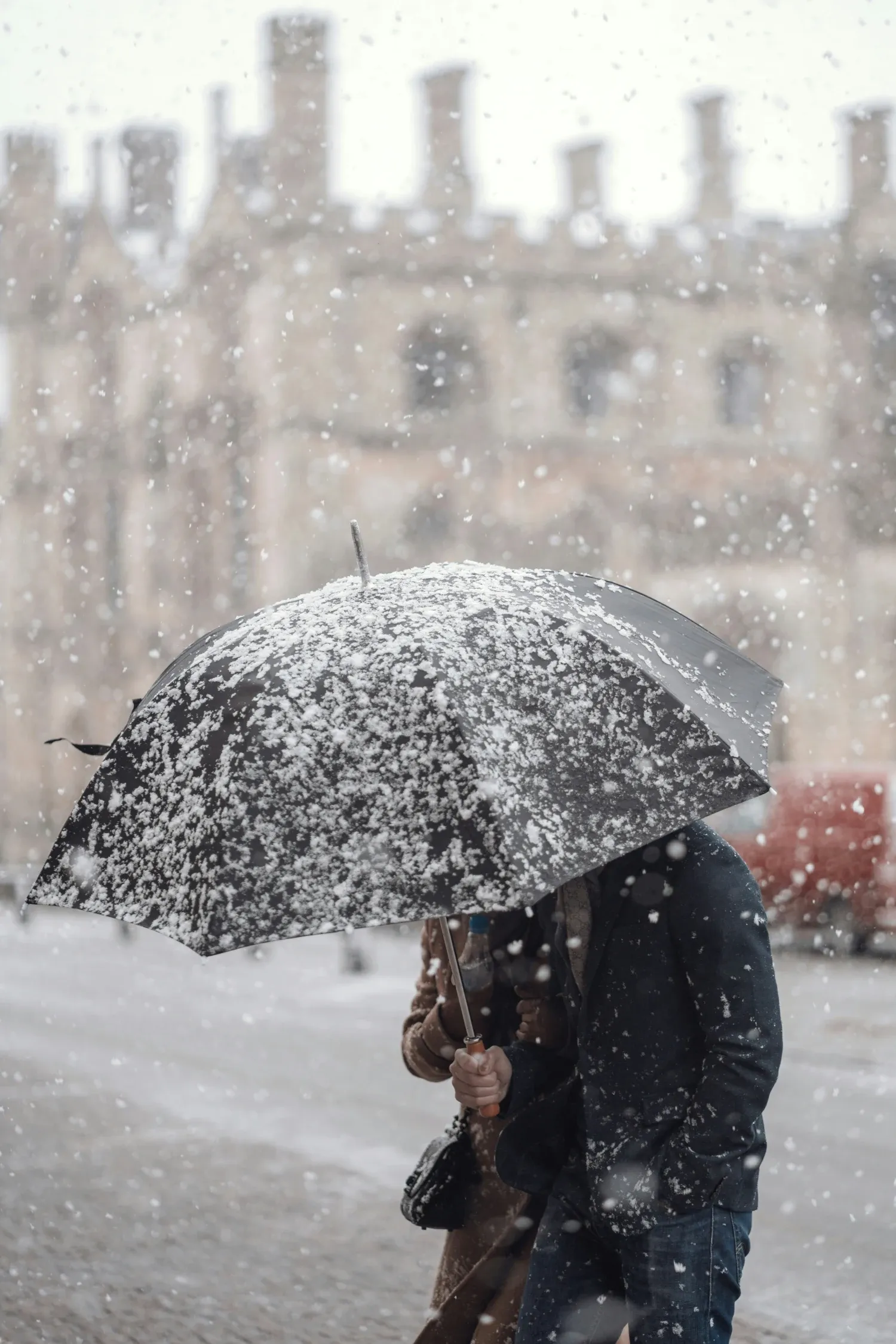 A man walking with an umbrella through a snow storm