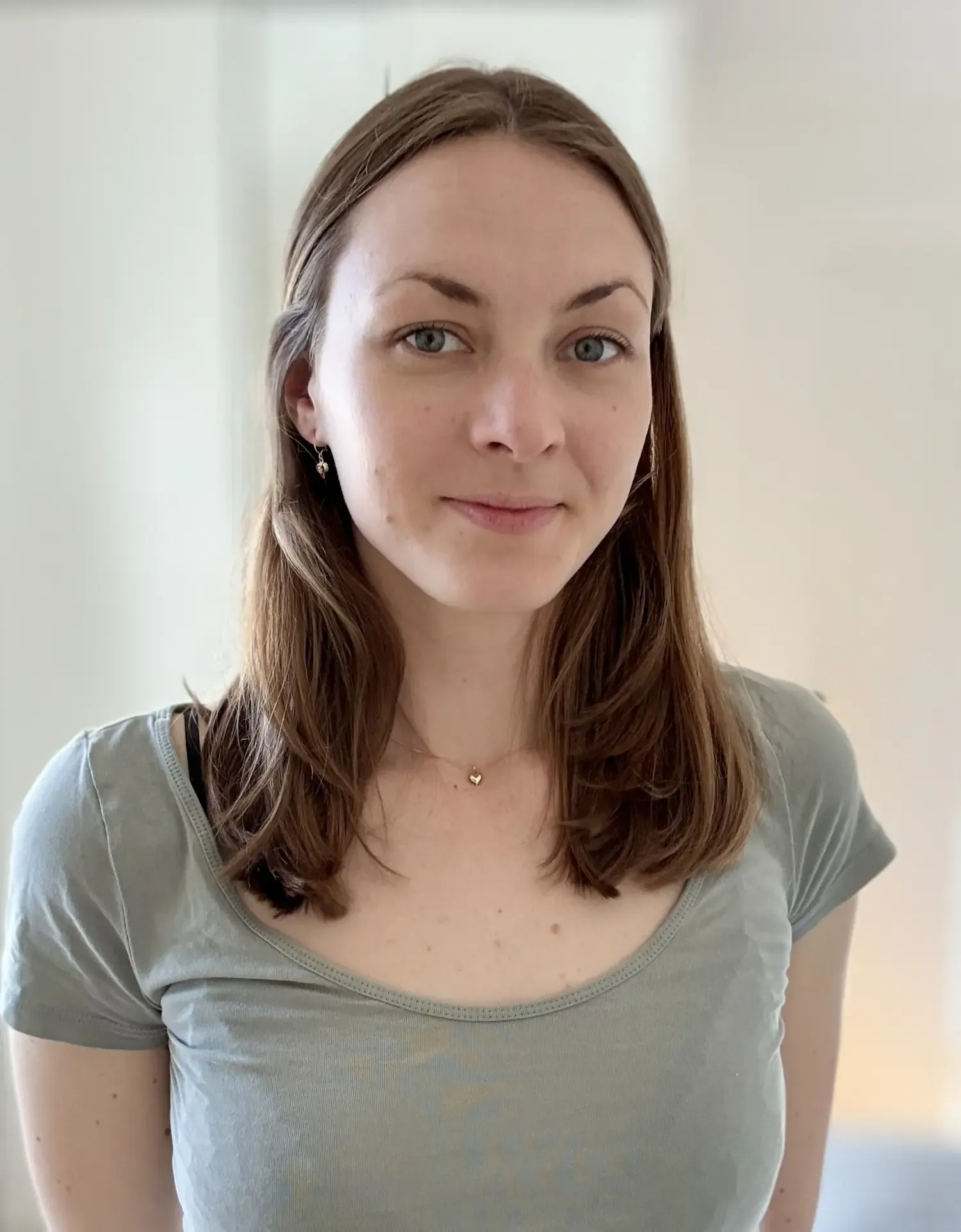 Portrait of woman with dark hair and light grey t-shirt.