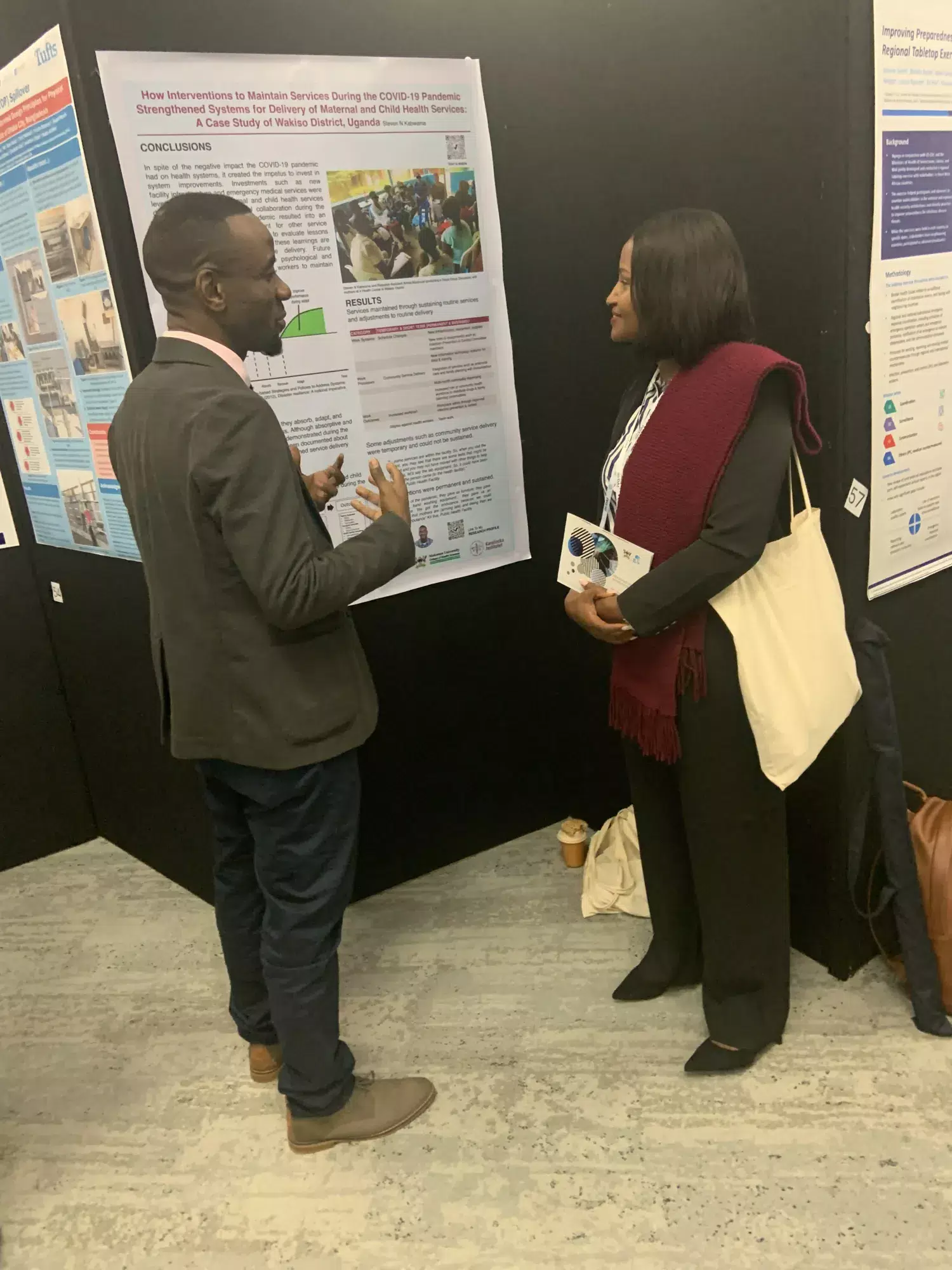 Steven Kabwama talking with woman in front of his poster at the Global Health Security Conference.