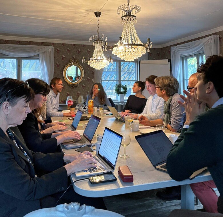 People sitting around a table, talking, having breakfast and making notes