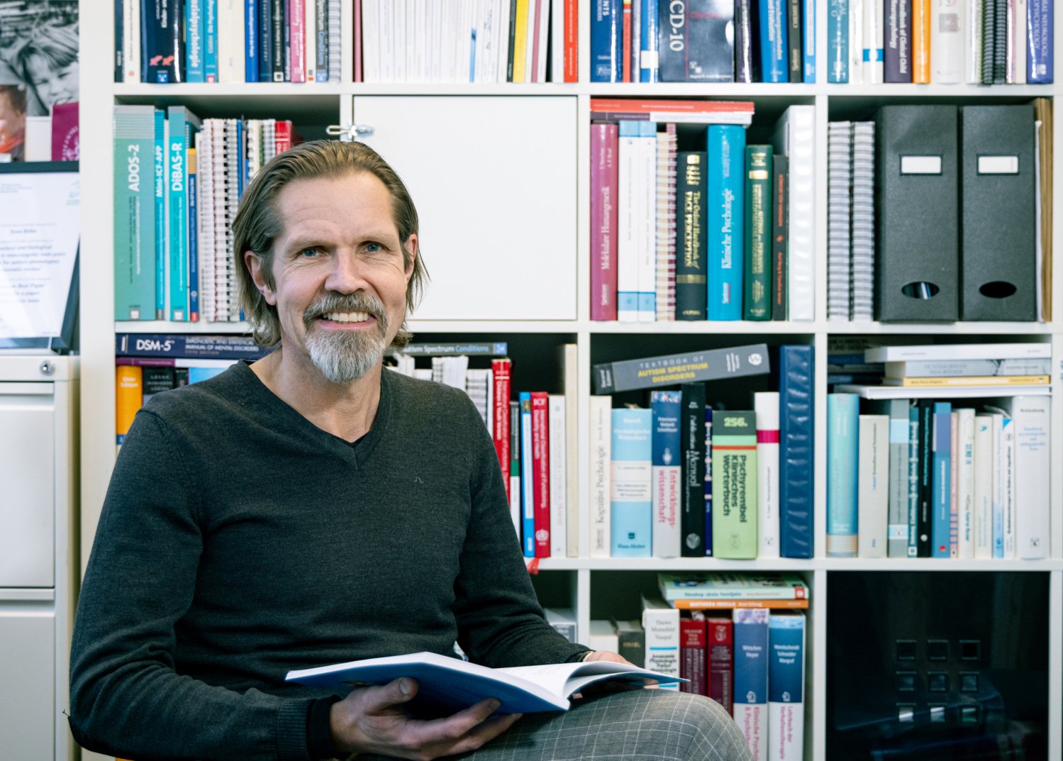Smiling man infront of a book case.