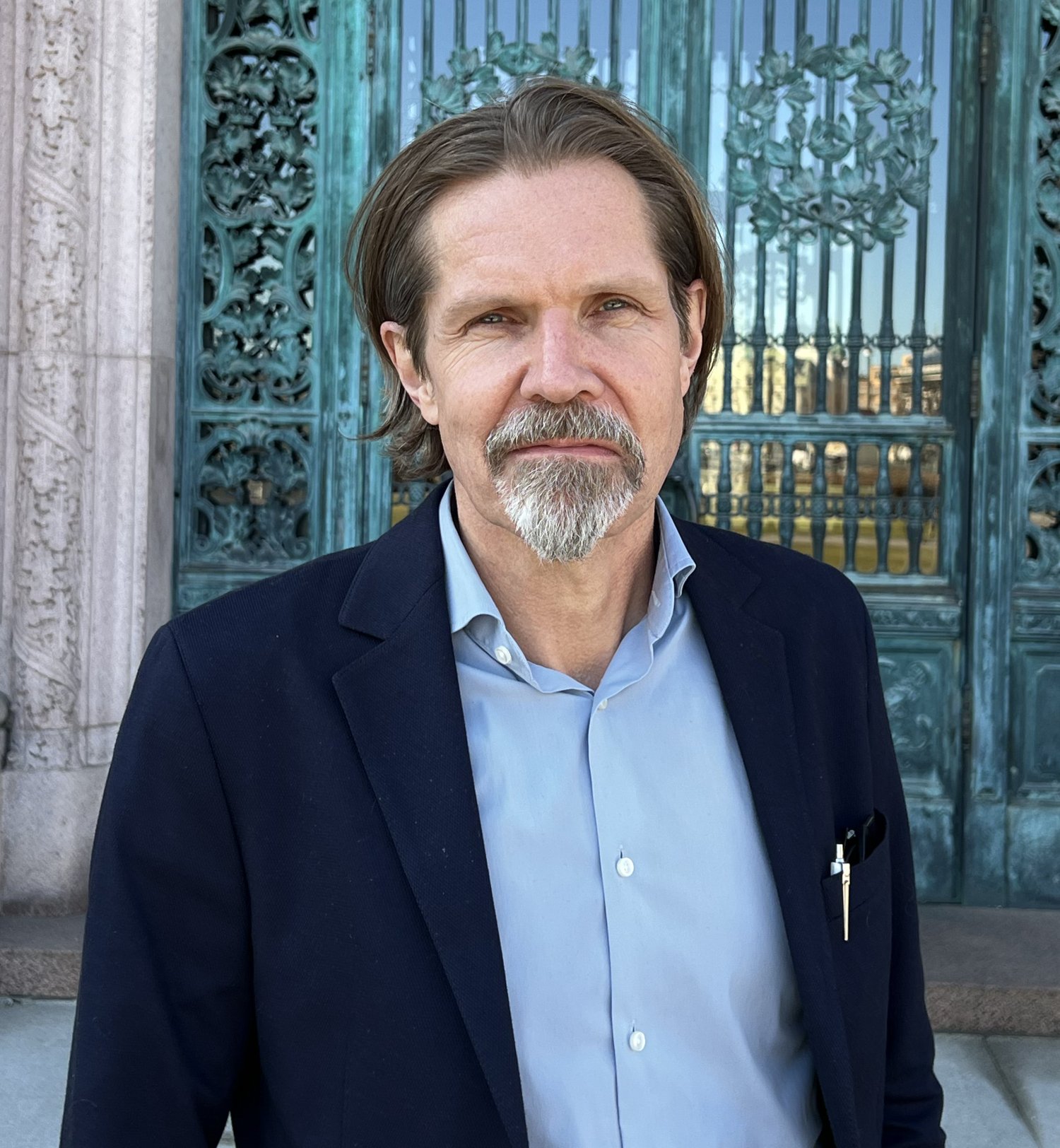 Photo of a man infront of large doors.