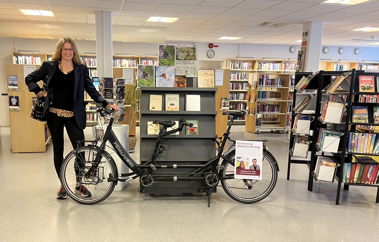 Pernilla Alencar Siljehag has finished the tandem tour and is now standing in the library leaning against the tandem bike.