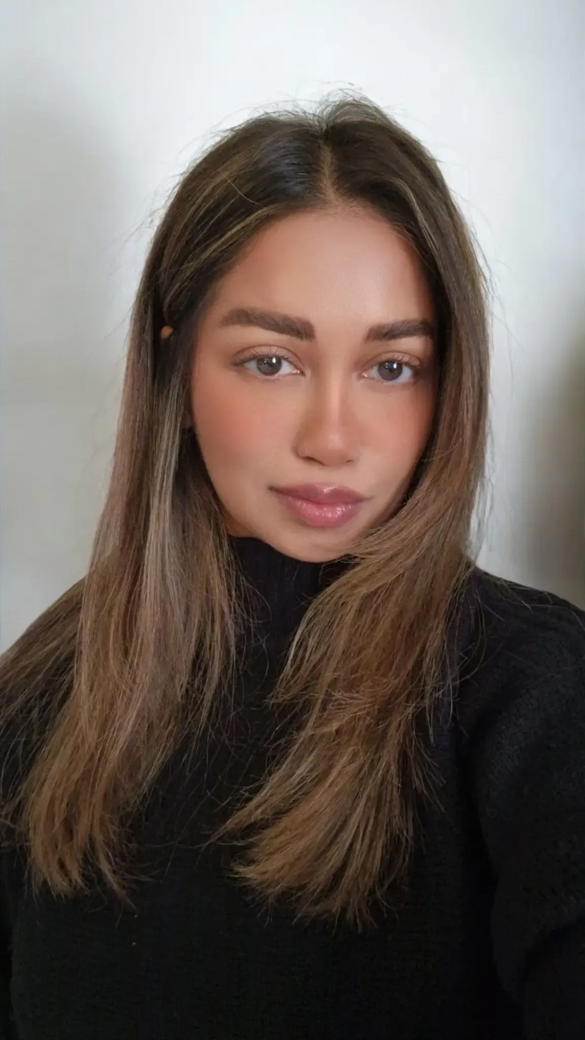 Portrait of a woman with long, dark hair, wearing a black turtleneck.