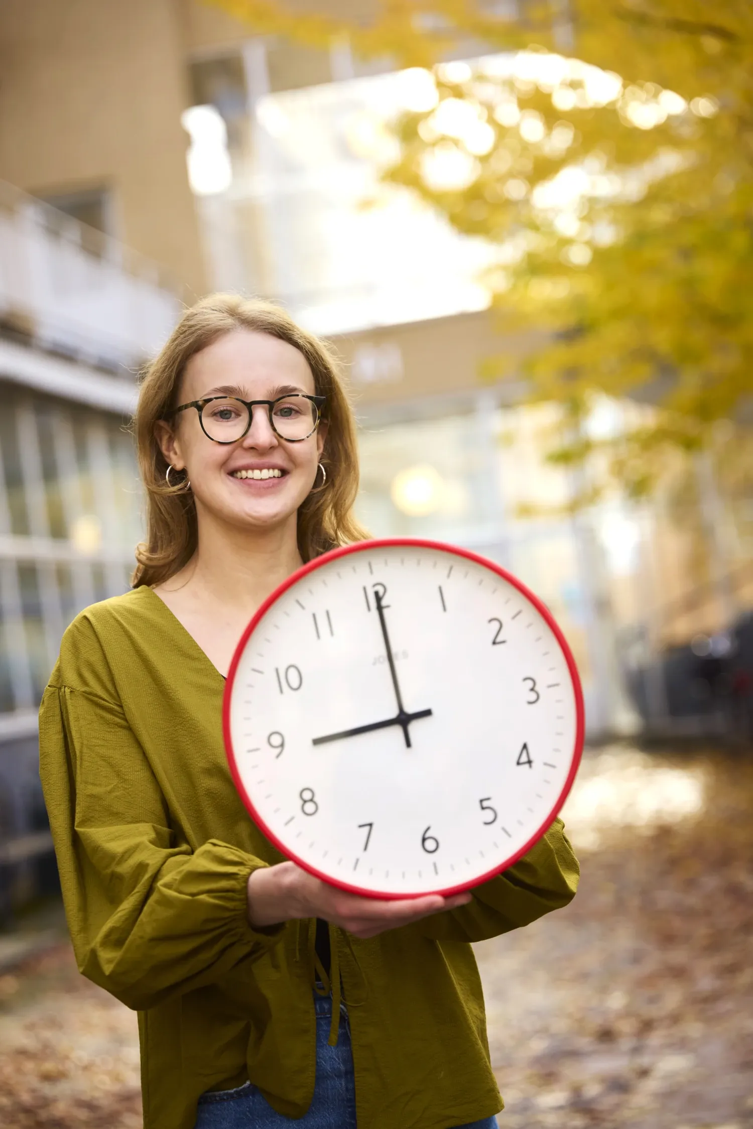 Researcher Theresa Lemke holding a clock displaying 9 am.