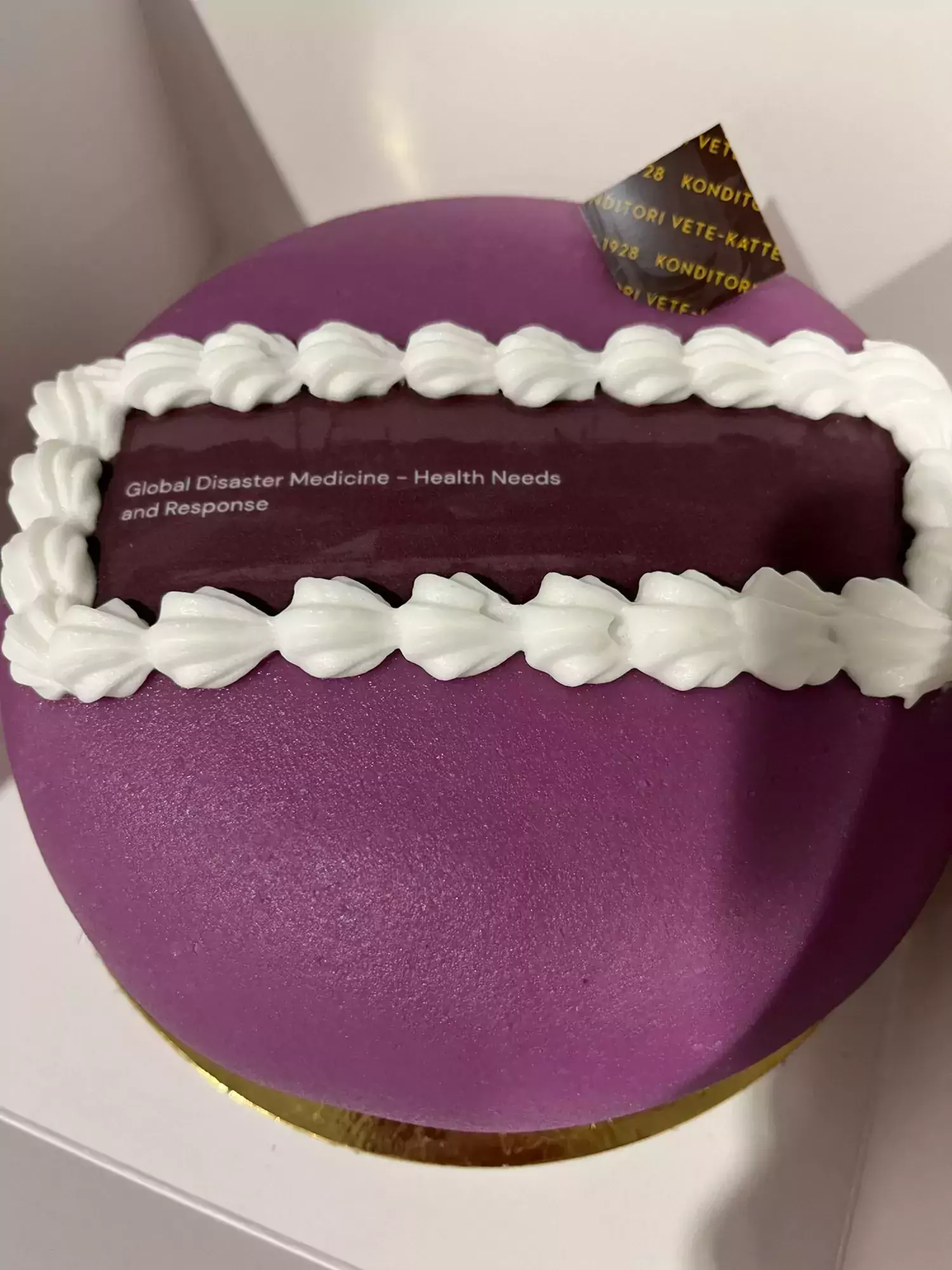 Cake with purple frosting and the words Global Disaster Medicine - Health Needs and Response written on it