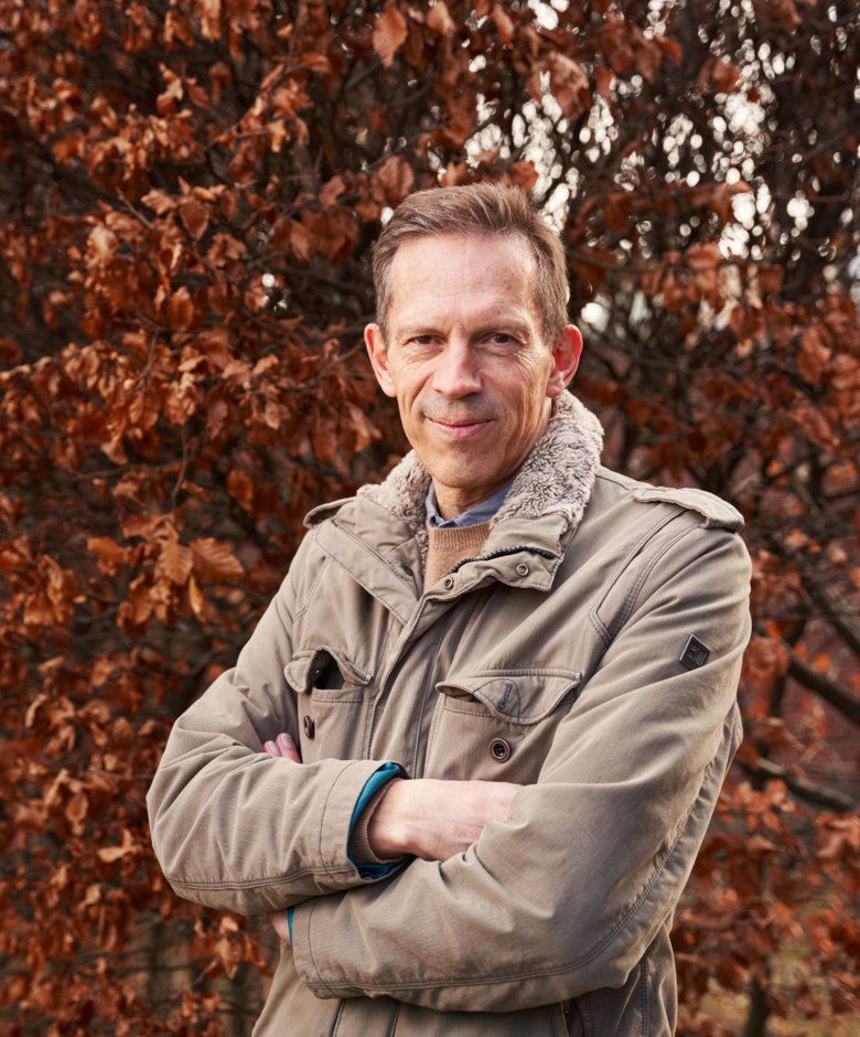 Thomas Perlmann outdoors, in front of a colorful deciduous tree.