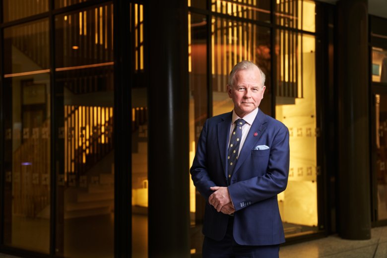 Ole Petter Ottersen with his hands crossed in front of him and stairs in the background.