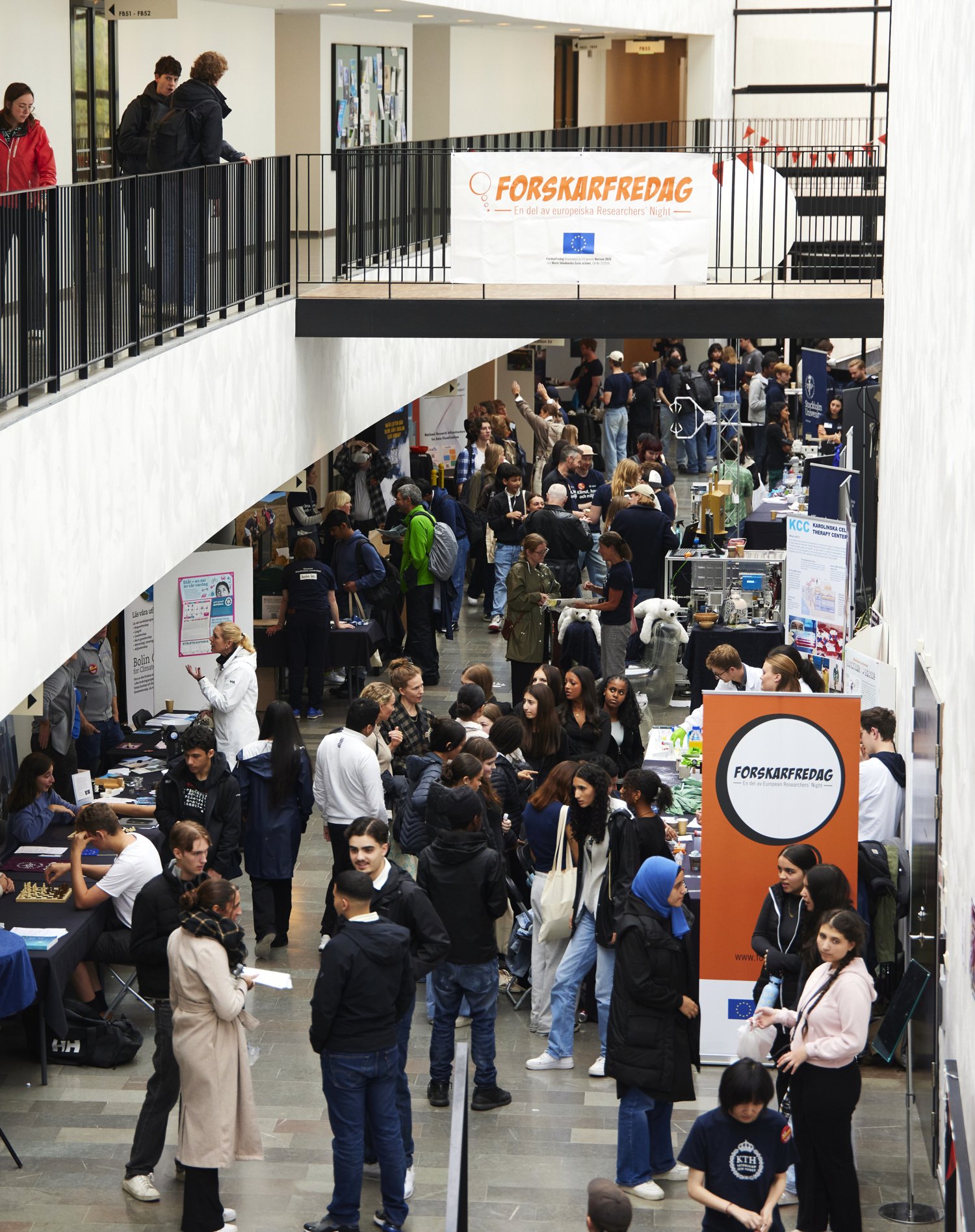 Many people around exhibition tables in a light and spacious room.