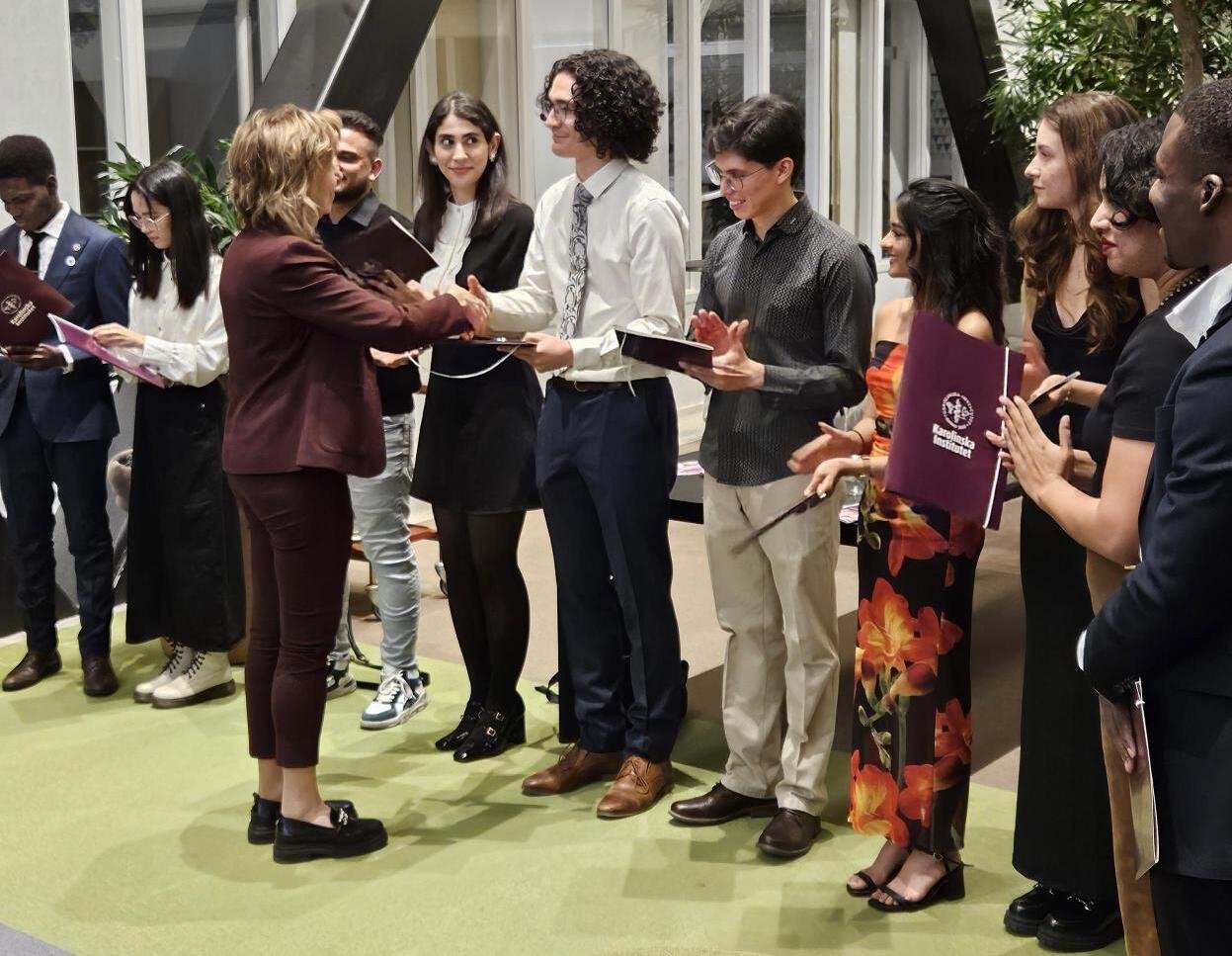 KI student and scholarship holders are lined up and one of them is shaking hands with KI's president.