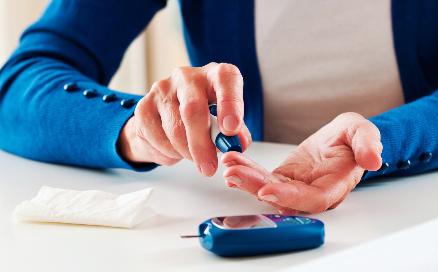 Blood glucose monitoring; woman stings her finger.