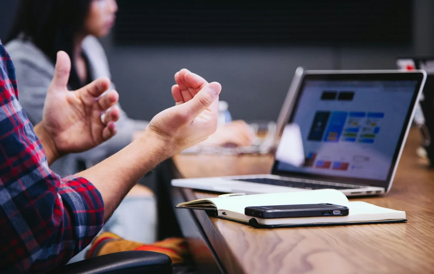 Two hands making a big gesture infront of a laptop