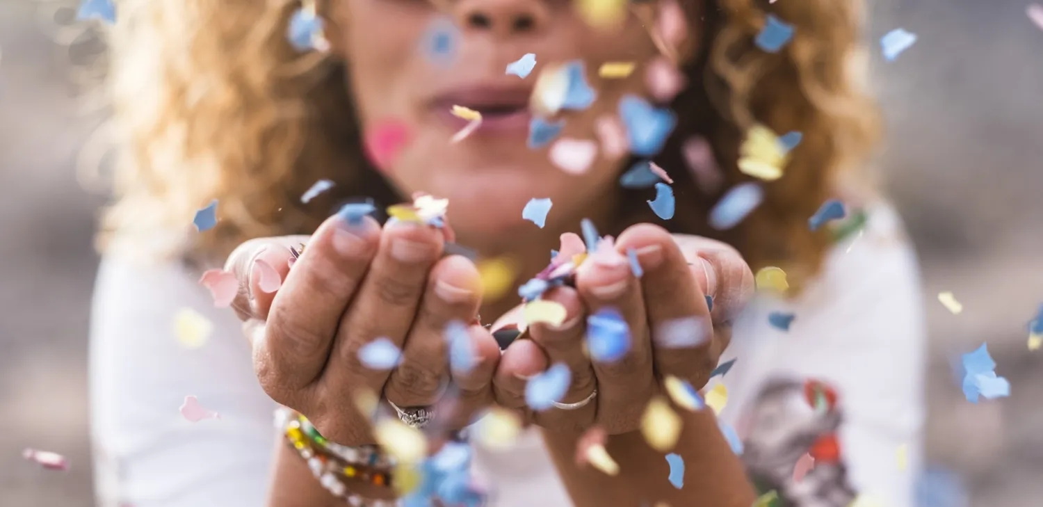 Photo of woman blowing confetti.