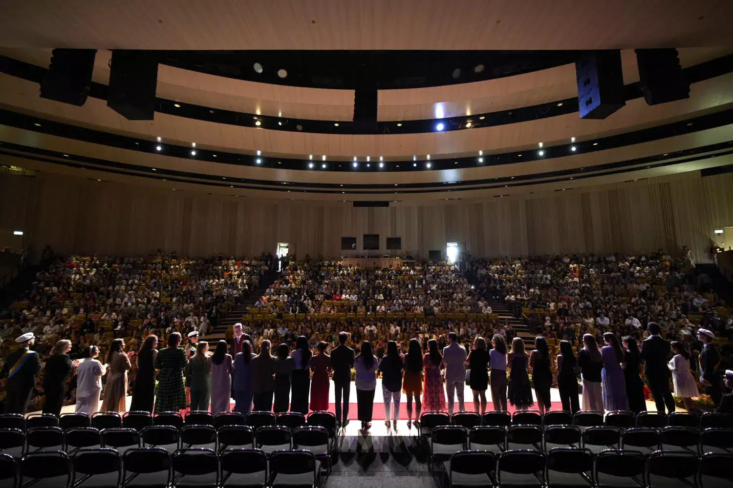 Students from a program lined up on the Erling Persson Hall stage photographed from behind.