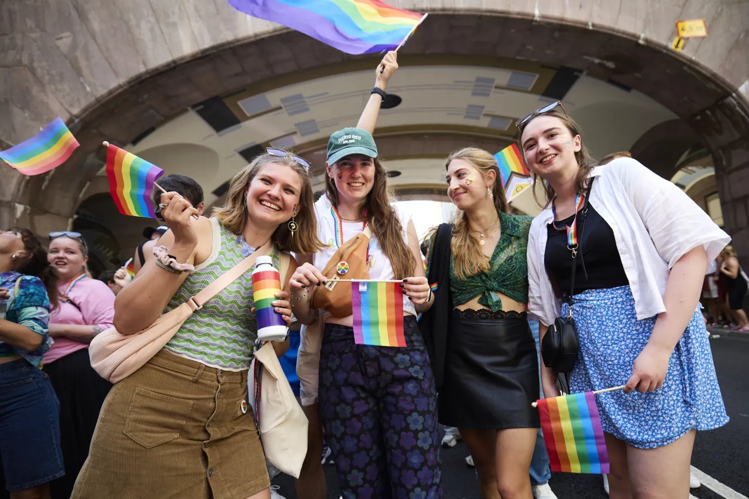 Alina Lapp, Maureen Verdier, Teresa Reindl and Katharina Schormair smiling in the street at the parade holding rainbow flags.