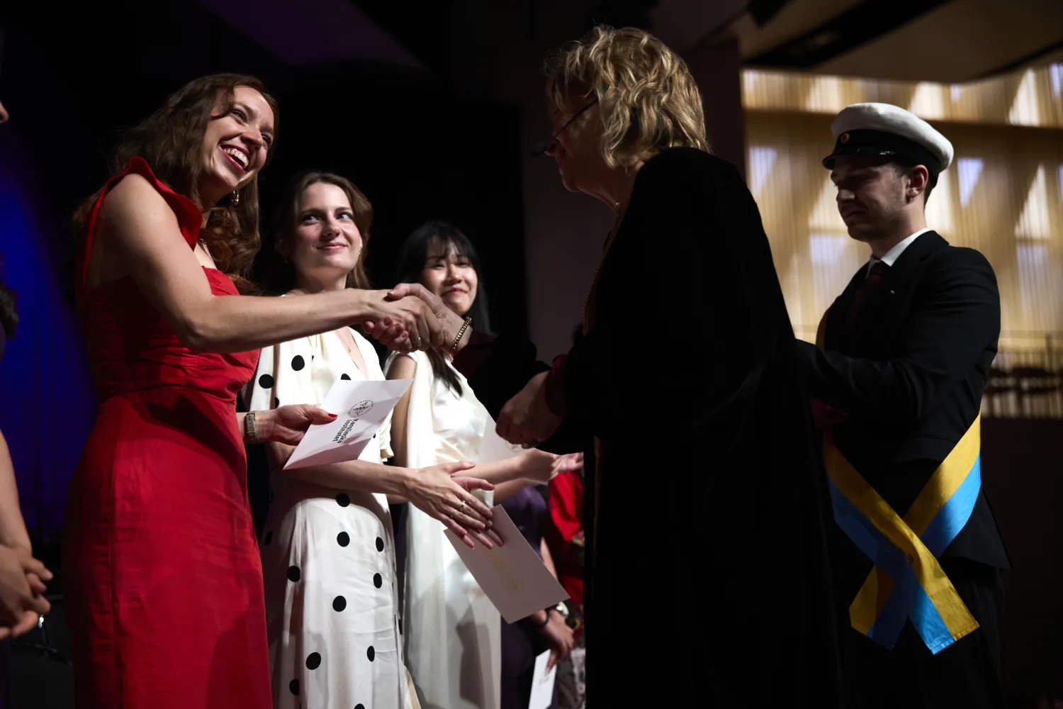 Graduating students receive their envelopes from KI President Annika Östman Wernerson.