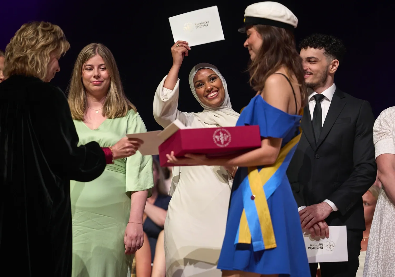 Student happily waving envelope on stage.