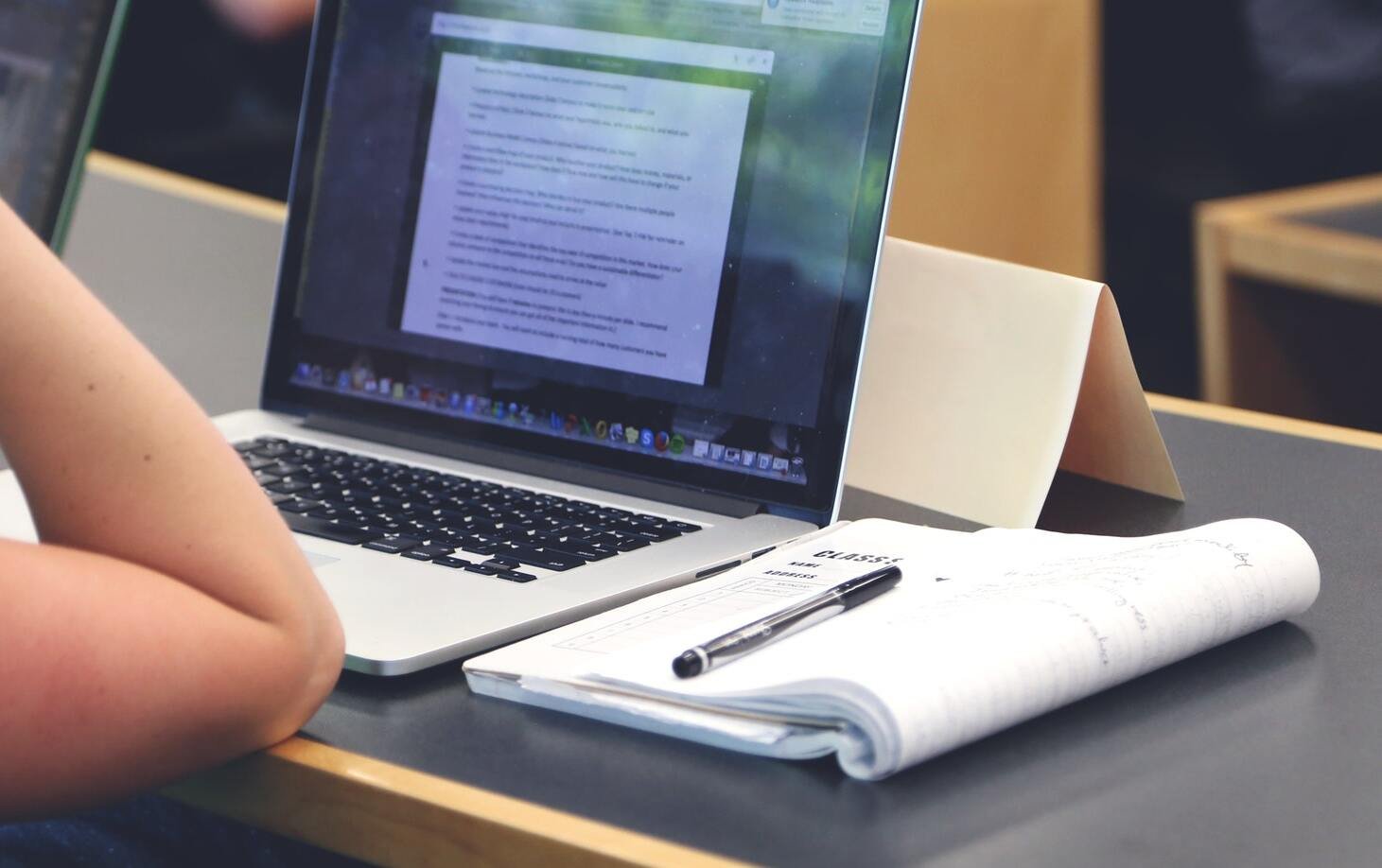 Doktorand på föreläsning med dator och anteckningsblock.