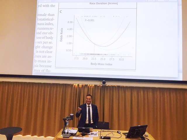 Nicola Orsini standing in a lecture hall in front of a presentation, looking happy.