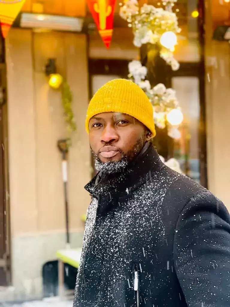 Sergio Nhassengo in a yellow beanie and black coat outside covered in snow.
